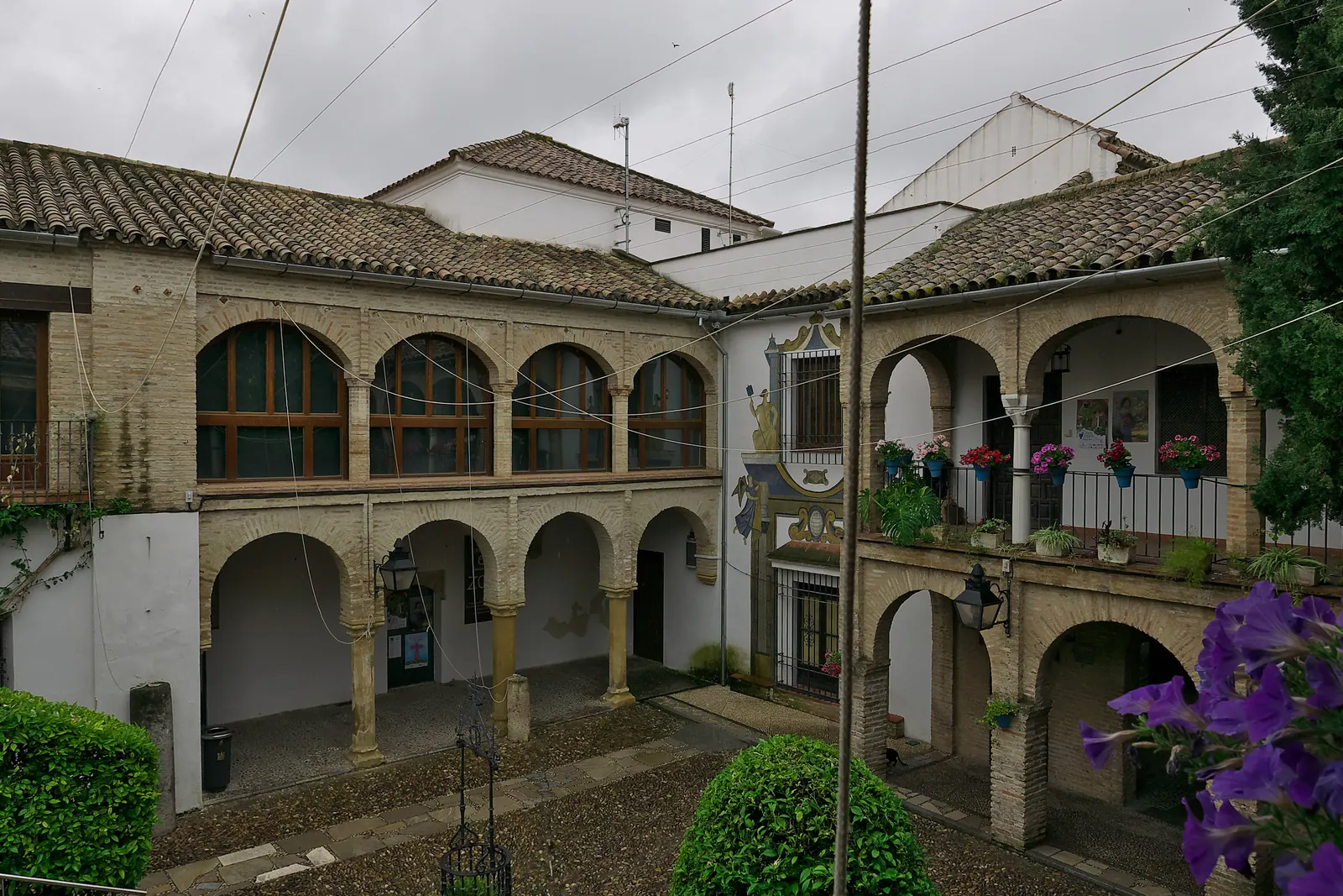 Dvoupatrové arkádové nádvoří Patio del Zoco v historickém centru Córdoby, pohled shora, s taškovými střechami a květinami